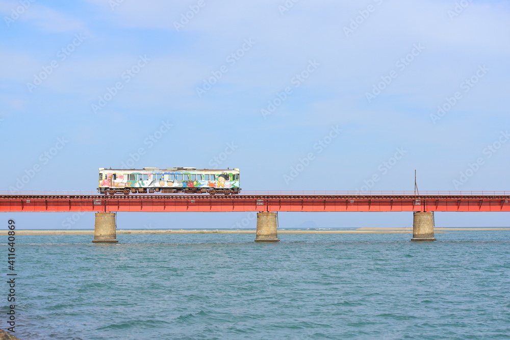 Fototapeta premium 赤い鉄を橋の上を走るカラフルな車両