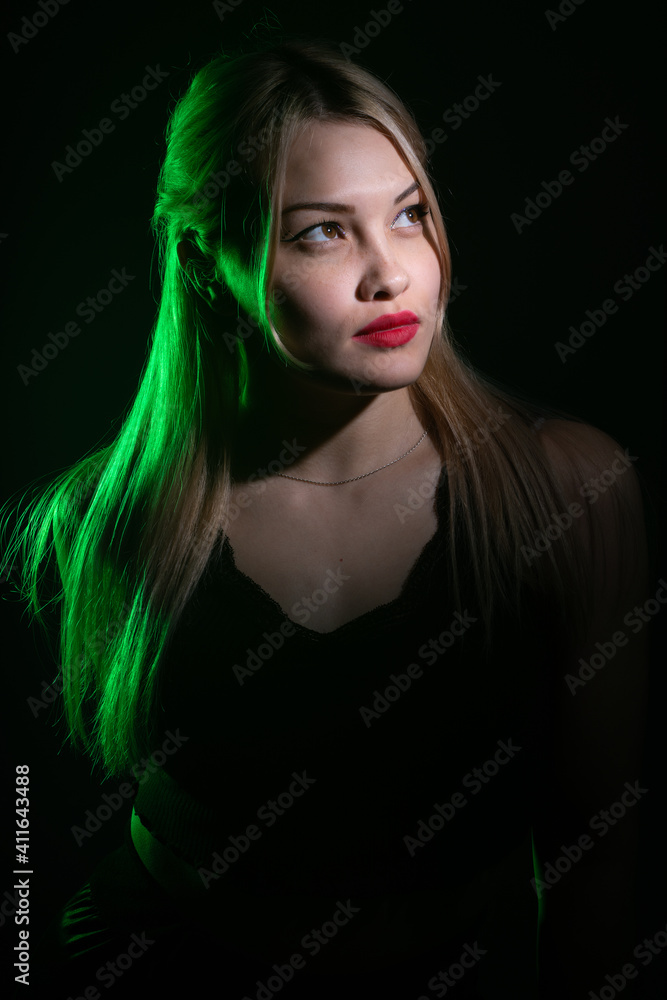 portrait of a blonde girl with bright makeup in green light