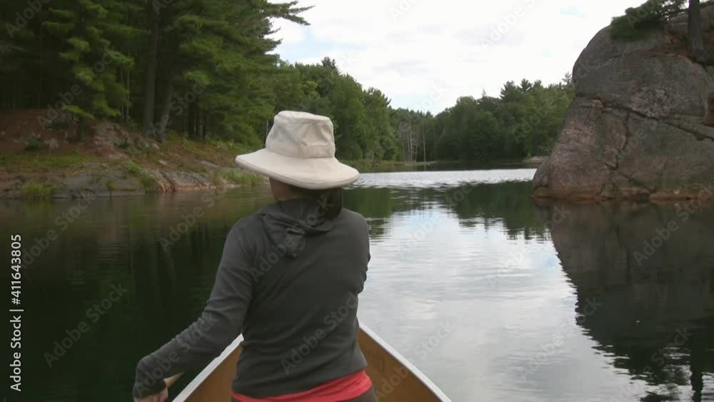 Woman paddles canoe. Rocky channel. POV from stern. Canoe tripping in Ontario, Canada.
Woman paddles canoe. Rocky channel. POV from stern. Canoe tripping in Ontario, Canada.