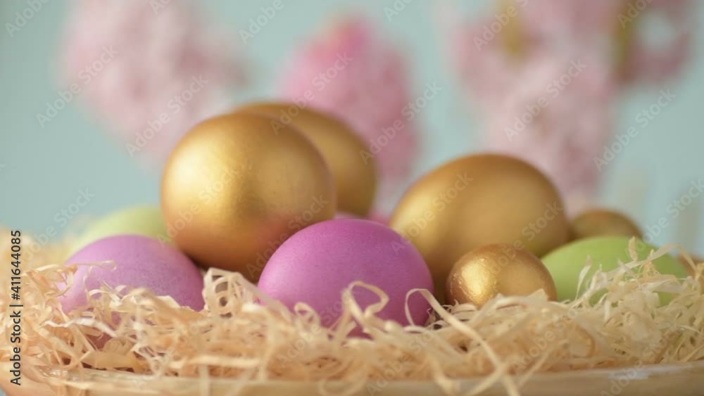 Colourful Easter eggs of pink, golden and green colour lie in straw spinning around on blurred light blue background with pink and magenta hyacinth flowers. Spring Christian holidays design concept
Colourful Easter eggs of pink, golden and green colour lie in straw spinning around on blurred light blue background with pink and magenta hyacinth flowers. Spring Christian holidays design concept