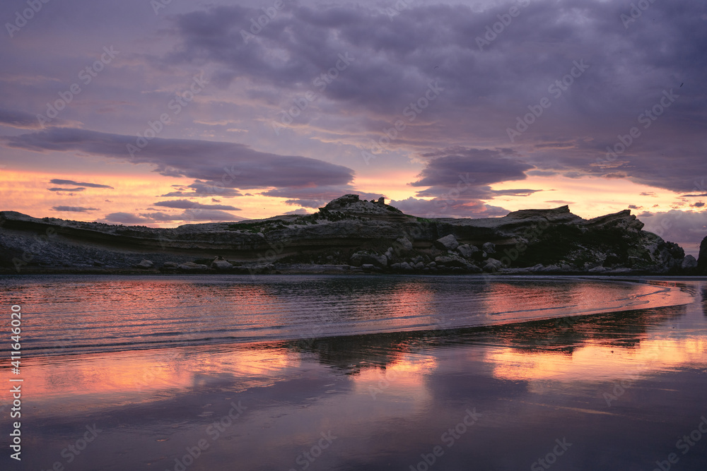Amazing sunset at the beach with cliffs reflected on the water. Castle Point, New Zealand Amazing sunset at the beach with cliffs reflected on the water. Castle Point, New Zealand