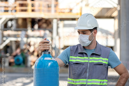 The worker is checking to the industrial compressed gas cylinder in the factory. A gas cylinder is a pressure vessel for storage and containment of gases at above atmospheric pressure. photo