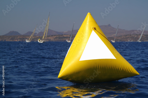 yellow sail boat race marker floating on aegean sea.  Mock up poster on the yellow buoy photo