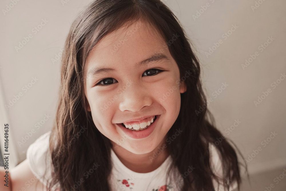 Close up urban lifestyle portrait of a confident, charming and gorgeous mixed race child face, multiethnic Asian girl with beautiful curly hair, smiling at camera Close up urban lifestyle portrait of a confident, charming and gorgeous mixed race child face, multiethnic Asian girl with beautiful curly hair, smiling at camera