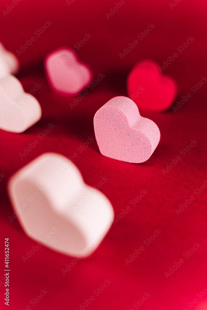 A little pink heart of sponge with with another hearts of sponge situated together on a red background. San Valentine's day backgrounds concept A little pink heart of sponge with with another hearts of sponge situated together on a red background. San Valentine's day backgrounds concept