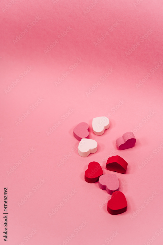 Some little hearts of sponge with different colors spreading on a pink background. San Valentine's day backgrounds concept