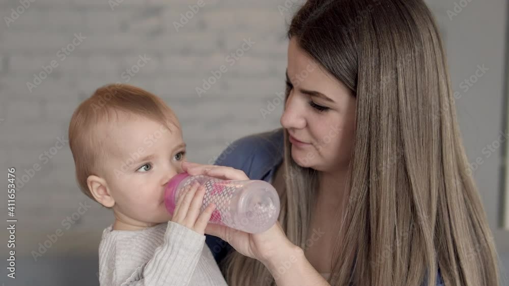 Little thirsty girl drinking water from bottle her mother giving her lunch break Little thirsty girl drinking water from bottle her mother giving her lunch break
