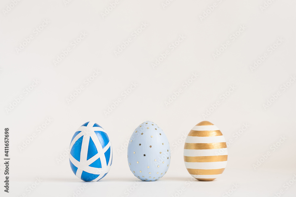 Three Easter golden decorated eggs on white background. Minimal easter concept. Happy Easter card with copy space for text. Top view, flatlay. Three Easter golden decorated eggs on white background. Minimal easter concept. Happy Easter card with copy space for text. Top view, flatlay.