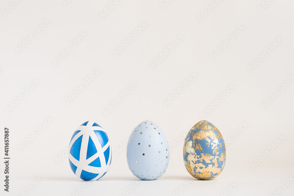 Three Easter golden decorated eggs on white background. Minimal easter concept. Happy Easter card with copy space for text. Top view, flatlay. Three Easter golden decorated eggs on white background. Minimal easter concept. Happy Easter card with copy space for text. Top view, flatlay.