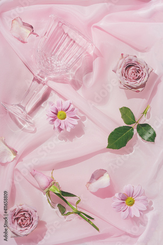 Pink rose flowers in water with silk fabric and champagne glass. Valentines or woman's day background design. Minimal flat lay nature.