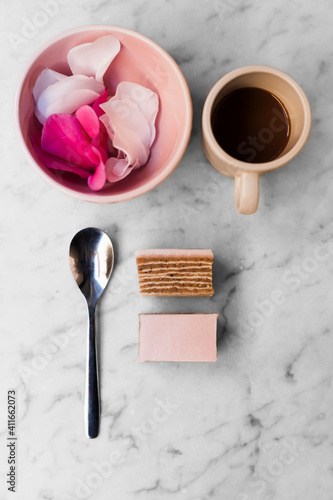Cup of coffee with a spoon and a rose pink cake