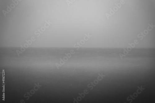 Eery photo of calm lake with snow and foggy sky in urban Chicago