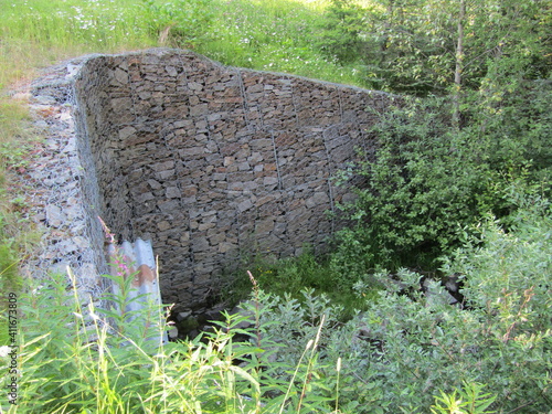 Gabion basket culvert. The mesh cells of the cubic form are filled with mountain stones of various shapes. Sun Peaks, British Columbia, Canada. photo