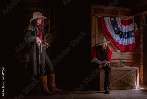 Cowgirl and cowboy posing with rifle gun on hand to show protected weapon ,vintage style.