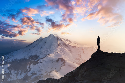 Adventure  Explore and Lifestyle Concept Composite. Adventurous Man Hiker on top of a Steep Rocky Cliff. Sunset or Sunrise. Landscape Taken from Washington  USA.