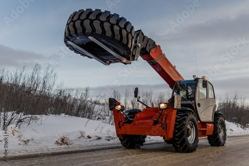 A telescopic forklift carries a tire.