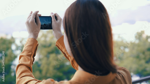 woman outdoors with a phone in her hands takes pictures on camera