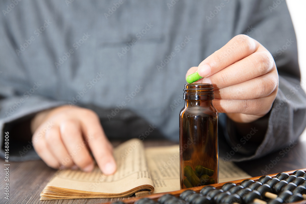 Traditional Chinese medicine pharmacists put the capsule into the medicine bottle in one hand and look up the information in the other hand Traditional Chinese medicine pharmacists put the capsule into the medicine bottle in one hand and look up the information in the other hand