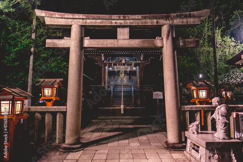 Tableau sur toile Girl and rabbit statue, stone torii gate and little shinto altar with bell and w