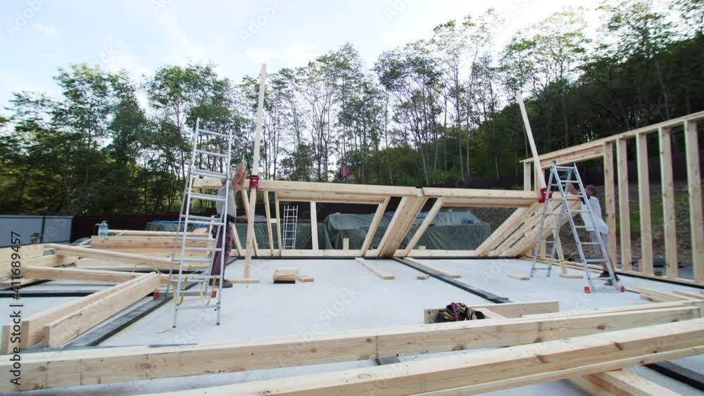 Timelapse of two builders lifting the front wall on the place. Wooden frame house building site Timelapse of two builders lifting the front wall on the place. Wooden frame house building site