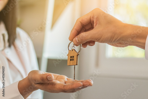 Close up hand of home,apartment agent or realtor was holding the key to the new landlord,tenant or rental.After the banker has approved and signed the purchase agreement successfully.Property concept.