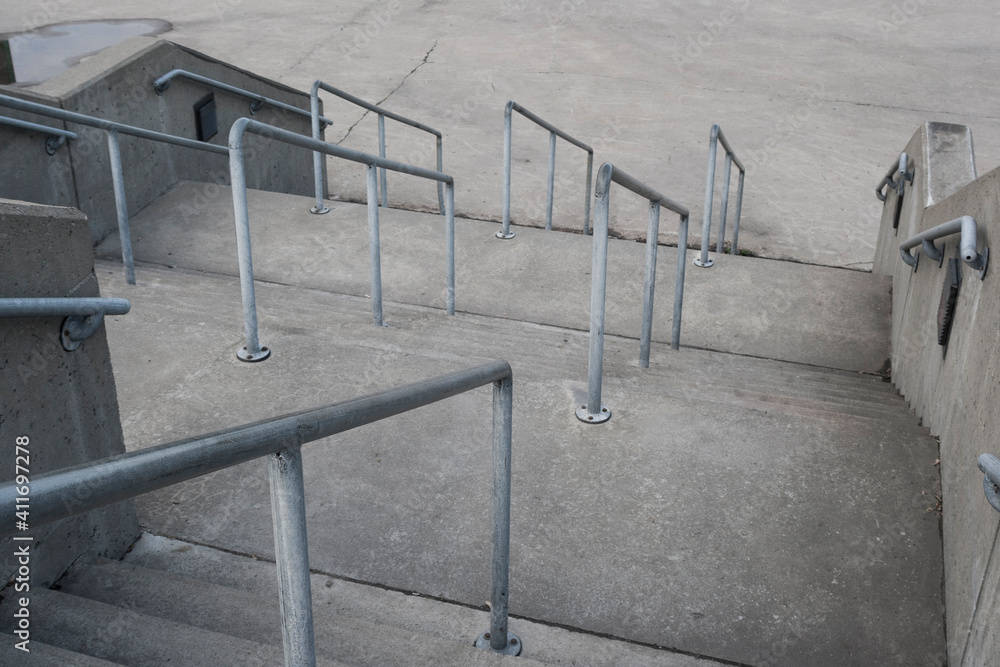 Grey stair stones with hand rail, view looking down with zig zag pattern, no person, interpretation for business or leadership Grey stair stones with hand rail, view looking down with zig zag pattern, no person, interpretation for business or leadership