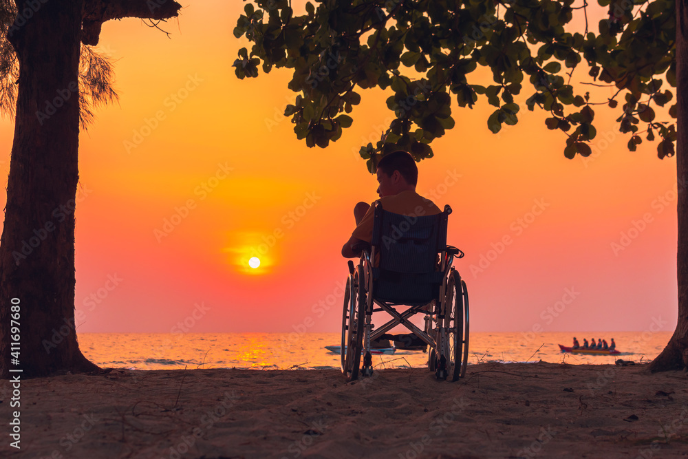 Obraz premium Asian special child on wheelchair on the sea beach with sunset on travel time in holiday family and learning about nature around the sea,Lifestyle in the education age kids,Happy disabled kid concept.