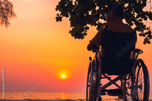 Asian special child on wheelchair on the sea beach with sunset on travel time in holiday family and learning about nature around the sea,Lifestyle in the education age kids,Happy disabled kid concept.