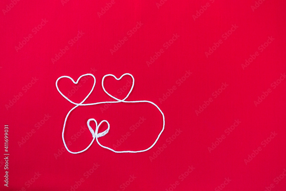 White cotton thread arrange in heart shape with space on red fabric background, love and romance concept, valentine day background