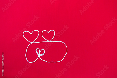 White cotton thread arrange in heart shape with space on red fabric background, love and romance concept, valentine day background
