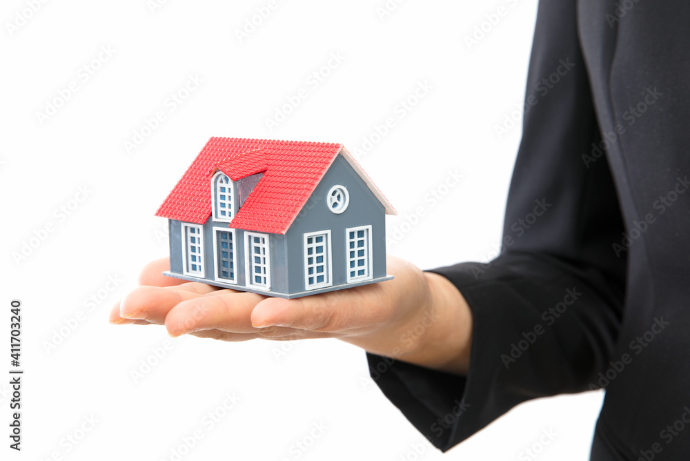 Real estate salesmen hold small house model in front of white background Real estate salesmen hold small house model in front of white background