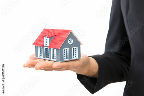 Real estate salesmen hold small house model in front of white background