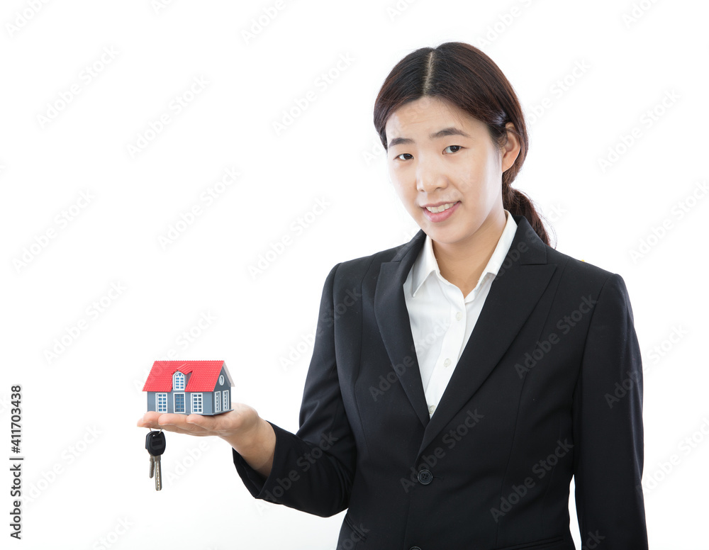 The real estate saleswoman holds the model and key of the small house in front of the white background The real estate saleswoman holds the model and key of the small house in front of the white background