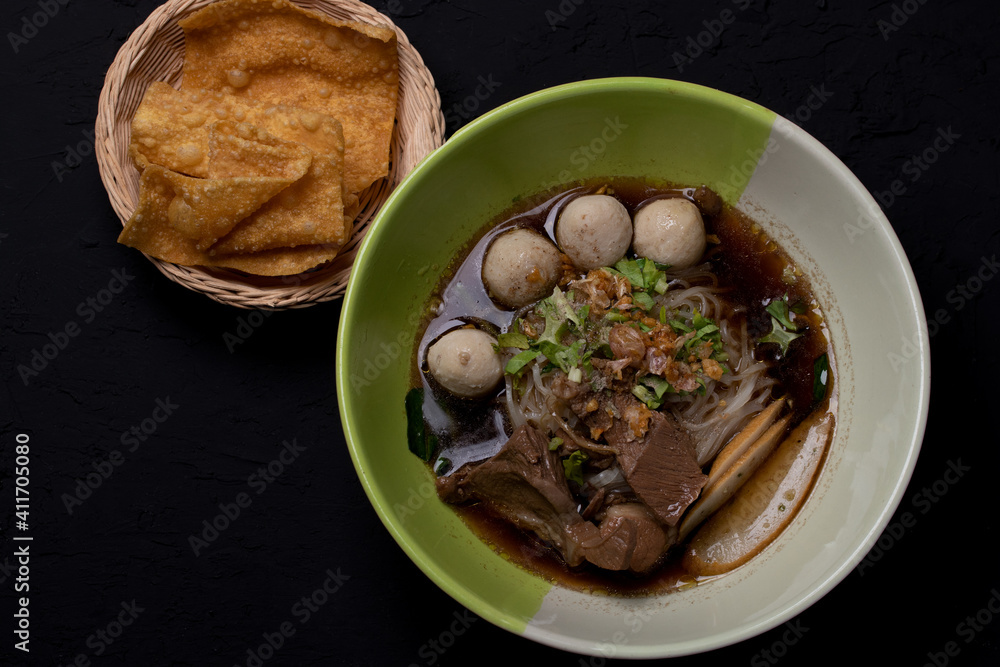 Braised pork noodles in a cup on a black background Braised pork noodles in a cup on a black background