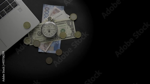 laptop, stopwatch and money on a black background
