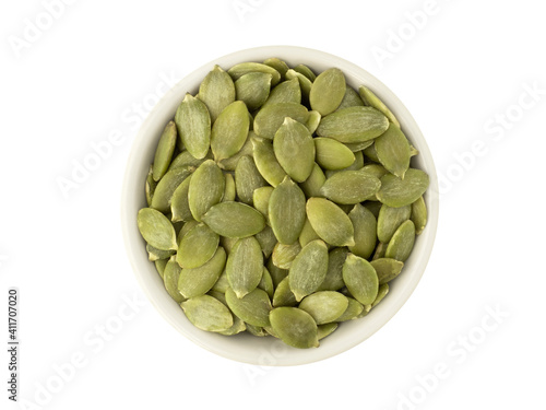 Organic pumpkin seeds in white ceramic bowl top view isolated on white background. Organic pumpkin seeds healthy ingredients food concept.