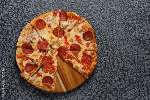 Pepperoni pizza, on a black textured background. Italian food concept. Close-up.