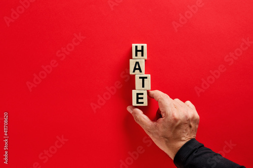 Photography Male hand arranging the wooden blocks with the word hate on red background