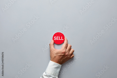 Businessman hand holding a red badge with the word sell. Decision to sell in finance or real estate