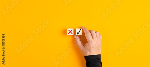 Right and wrong icons on wooden cubes with male hand choosing the right icon photo