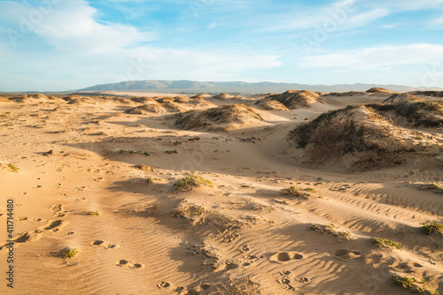 Sand dunes at sunset  silhouette of mountains  and beautiful cloudy sky on background