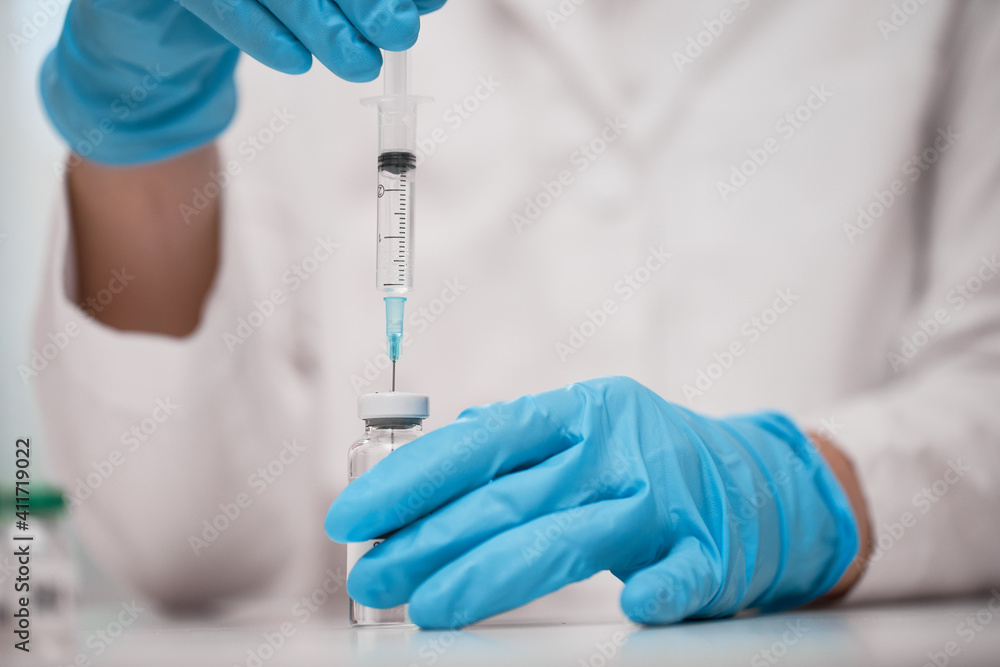 Doctor dials the vaccine into a syringe Doctor dials the vaccine into a syringe