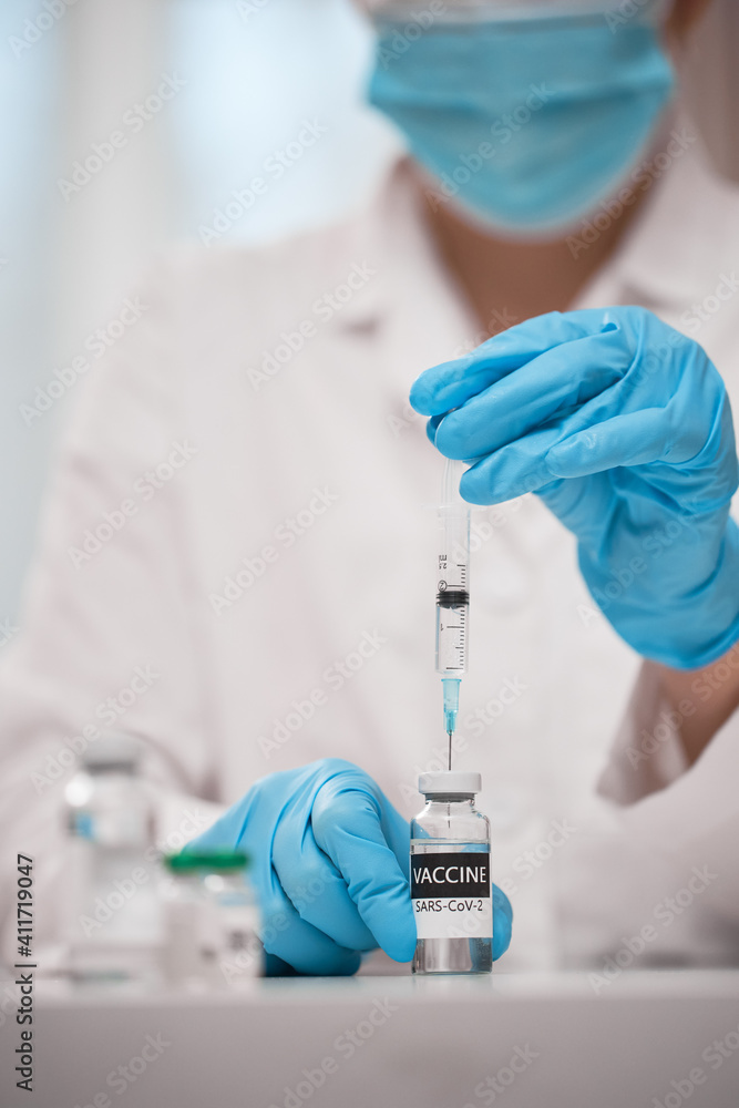 Doctor dials the vaccine into a syringe Doctor dials the vaccine into a syringe