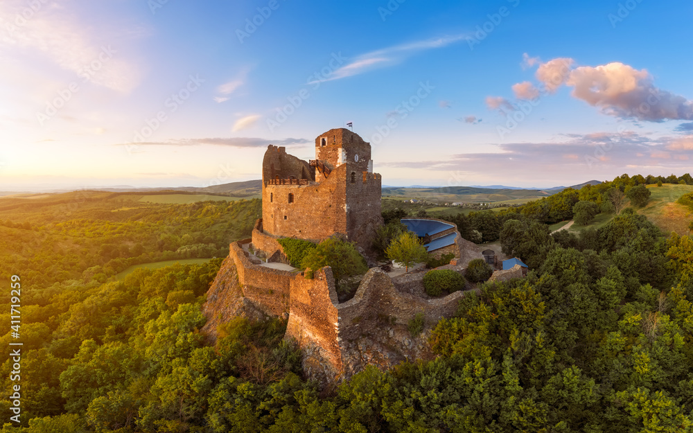 Historical monument in Hungary Mountains. Aerial landscape about a medieval castle ruins near by Holloko town. Panoramic landscape photo with forest and amazing sunset