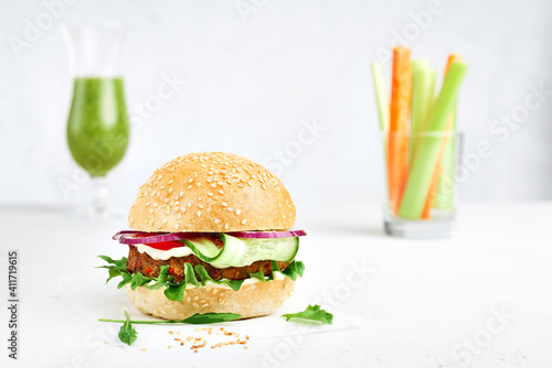 Veggie burger with celery smoothies, carrots and cerely on a white deck with copy space. photo