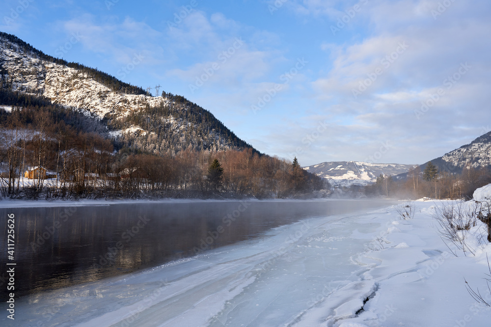 The river is about to freeze. It is very cold and the river is much warmer than the air, therefore the smoke or the damp from the river. Shot at Gol, Norway in February. Minus 20 degreases Celsius. 