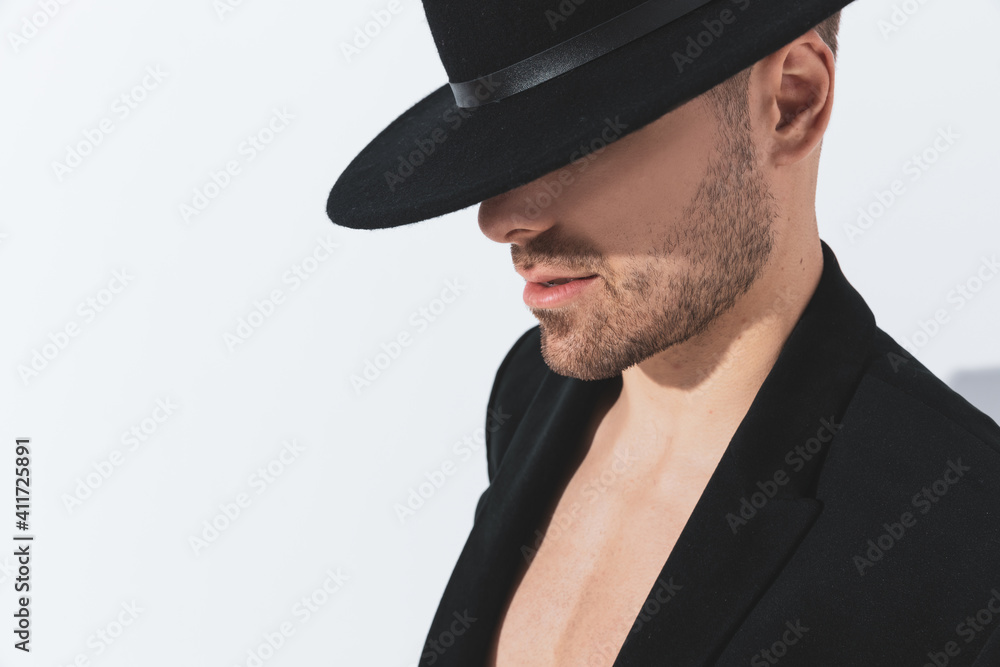 side view of dramatic cool guy in jacket looking down and covering face side view of dramatic cool guy in jacket looking down and covering face
