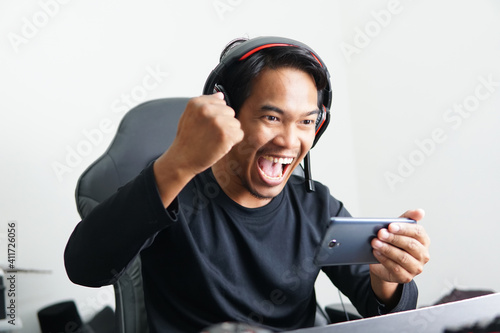 Asian Gamer playing mobile game with excited expression emotion. Winning esport game