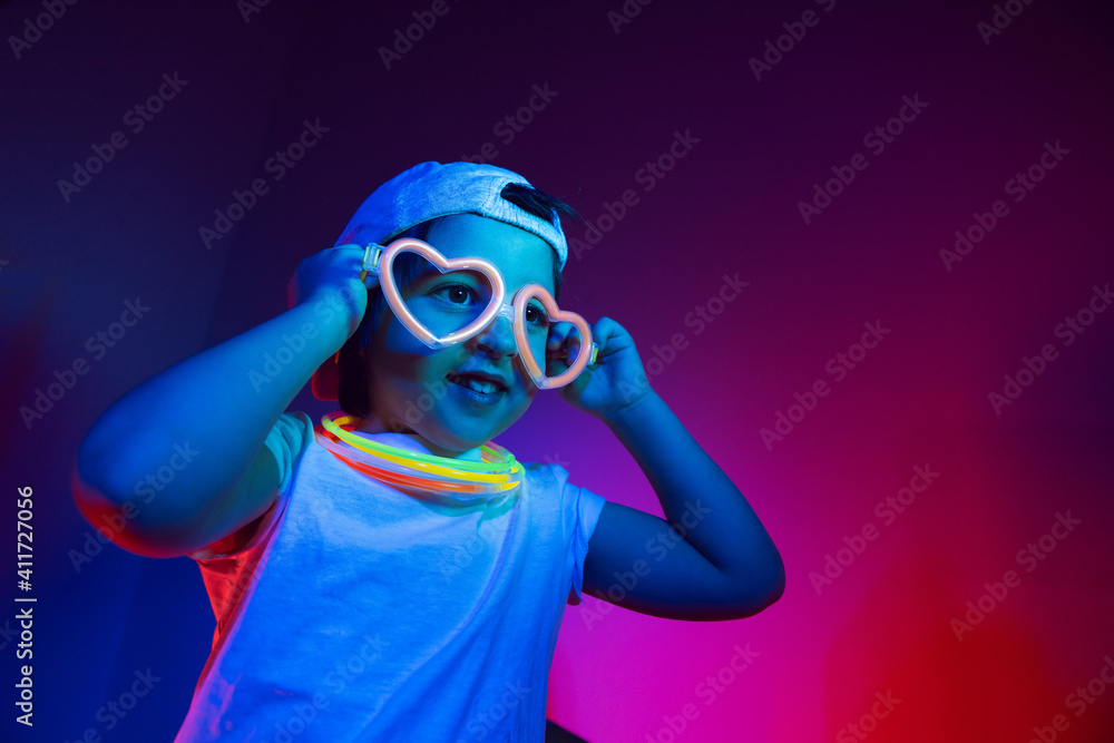 cyberpunk boy child in a white T shirt and large headphones listening to music on the background of the wall