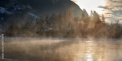 The river is about to freeze. It is very cold and the river is much warmer than the air, therefore the smoke or the damp from the river. Shot at Gol, Norway in February. Minus 20 degreases Celsius. 